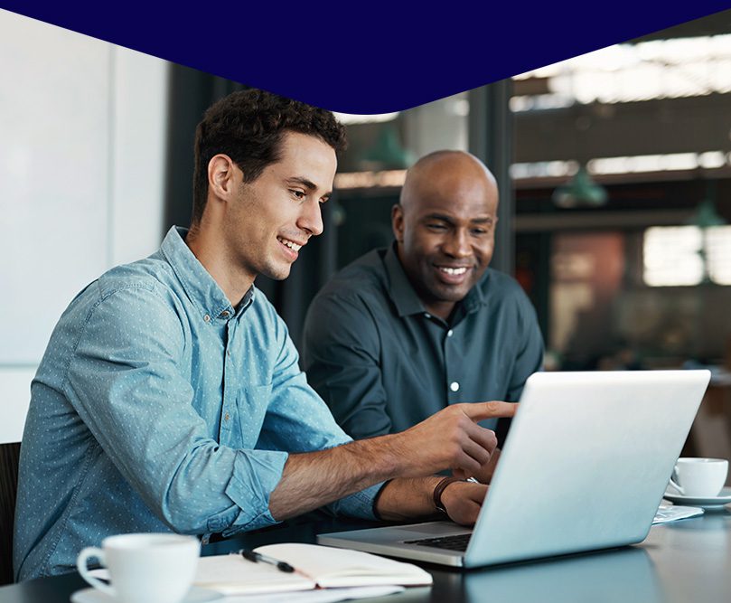 two men chatting and showing results on a laptop